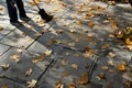 woman sweeping fallen leaves off a stone tiled patio