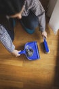 Woman sweeping floor and collecting dust onto a dustpan Royalty Free Stock Photo