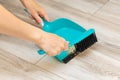 woman sweeping garbage into a plastic dustpan