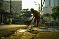 A woman sweeping the streets in the morning sun in Ho Chi Minh City Vietnam