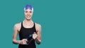 Woman swimmer smiling in swimming cap holds goggles in hands over isolated background Royalty Free Stock Photo