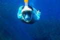Woman swimming in blue sea. Girl snorkeling in full-face mask. Snorkel with fish school underwater photo Royalty Free Stock Photo