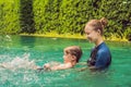 Woman swimming instructor for children is teaching a happy boy to swim in the pool