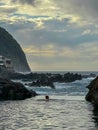 Porto Moniz - Woman swimming in natural lava pool Piscinas Naturais Velhas at sunset in coastal town Porto Moniz, Madeira