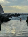 Porto Moniz - Woman swimming in natural lava pool Piscinas Naturais Velhas at sunset in coastal town Porto Moniz, Madeira