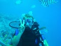 Woman swimming in open sea. Close up underwater photo. Diving girl in open water with stripe fishes Royalty Free Stock Photo