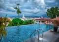 A woman is swimming in a panarama pool over a seaside resort