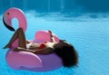 Woman in a swimming pool leisure on a giant inflatable giant pink flamingo float mattress in red bikini Royalty Free Stock Photo