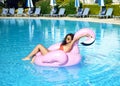 Woman in a swimming pool leisure on a giant inflatable giant pink flamingo float mattress in red bikini Royalty Free Stock Photo