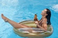 Woman in swimming pool on rubber ring relaxing while having vacation, enjoying summer season, spending time drinking fresh Royalty Free Stock Photo