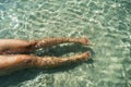 Woman swimming on the sea. Female legs under clear sea water. Realistic top view photo of a women's legs barefoot. Royalty Free Stock Photo