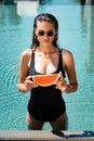 Woman in swimming suit with watermelon in pool