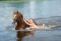 Woman swimming winth stallion in river Royalty Free Stock Photo