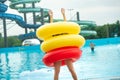 A woman in a swimsuit with rubber inflatable circles plays and has a good time near the pool of the summer water park Royalty Free Stock Photo