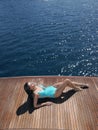 Woman In Swimsuit Sunbathing On Yacht's Floorboard