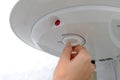 A woman switches the boiler to a higher or lower temperature. The concept of saving energy