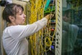 The woman switches the fiber wires in the server room. A specialist commutes an optical Internet cable in a rack with powerful Royalty Free Stock Photo