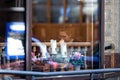 A woman at a table in a restaurant. View through the window. Street reflections in the glass