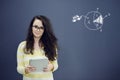 Woman with tablet in front of background with drawn business chart and icons. Royalty Free Stock Photo