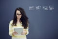 Woman with tablet in front of background with drawn business chart and icons. Royalty Free Stock Photo