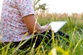 Woman with tablet outside. Young woman using tablet outdoor. Green grass in park on sunny summer day sitting on grass Royalty Free Stock Photo