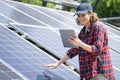Woman with tablet touching solar panel