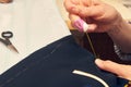 Woman tailor wrapped up in sewing jacket with needle and thread while sitting at working table. Suit tailoring in process of Royalty Free Stock Photo