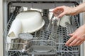 Woman take clean drinking glass from dishwasher machine. woman putts drinking glass to dishwasher machine to clean it