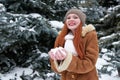 Woman take a handful snow in winter park at day. Fir trees with snow.