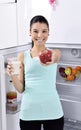 Woman take red apple and milk from fridge