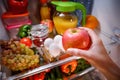 Woman takes the apple from the open refrigerator. Royalty Free Stock Photo