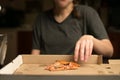 Woman takes a bite of the pizza and puts it in the box. Overeating and satiety Royalty Free Stock Photo