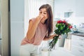 Woman takes dead roses out of vase feeling bad smell. Housewife taking care of coziness on kitchen