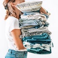 Woman takes in hands big pile blue and beige blankets, towels and other home textile Royalty Free Stock Photo