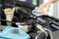 A woman takes matters into her own hands radiator refill. Mechanic performing car engine repair in an automotive service garage Royalty Free Stock Photo