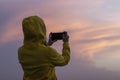 Woman takes photo of colored evening sky by smartphone. Royalty Free Stock Photo