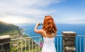 Woman takes photo of seaside landscape