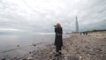 Woman takes photos on camera of sea in cloudy weather. Action. Professional photographer woman takes pictures of sea