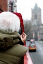A woman takes a picture of the Christ Church Cathedral on her cell phone, while riding a double deck tour bus around the city.