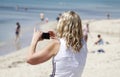 A woman takes a picture with her cell in Arenal beach