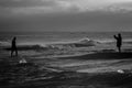 A woman takes a picture of a man standing in the sea.a black and white picture