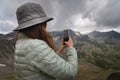 woman takes a picture on the phone while standing on top of a hill. Portrait of a tourist in the mountains Royalty Free Stock Photo