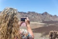 A woman takes pictures with her mobile phone in a desert landscape on the island of Tenerife on a very sunny day Royalty Free Stock Photo