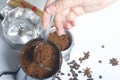 A woman takes a spoonful of ground coffee from a coffee grinder and puts it in a geyser coffee machine.