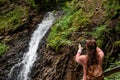 Woman takes a waterfall on the phone with a backpack behind her back