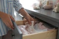 Woman taking baby clothes from open cabinet drawer in child room Royalty Free Stock Photo