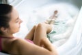 Woman taking a bath in bathtub. Hot bubble soap water and foam in tub. Happy smiling lady enjoying spa and wellness treatment.