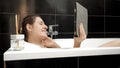 Woman taking a bath while staying connected with friends and family via a video call on her tablet computer. Authenticity and