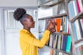 Woman taking book from library bookshelf. Young librarian searching books and taking one book from library bookshelf Royalty Free Stock Photo