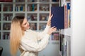 Woman taking book from library bookshelf. Young librarian searching books and taking one book from library bookshelf. Royalty Free Stock Photo